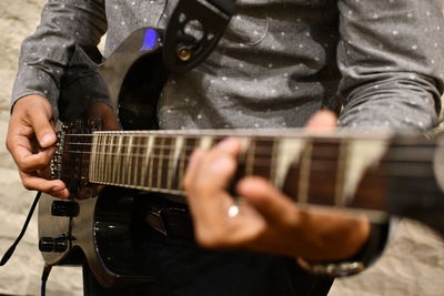 Midsection of man playing guitar