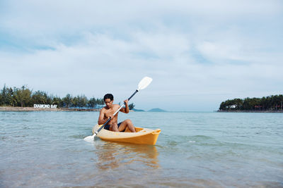 Man kayaking in sea against sky