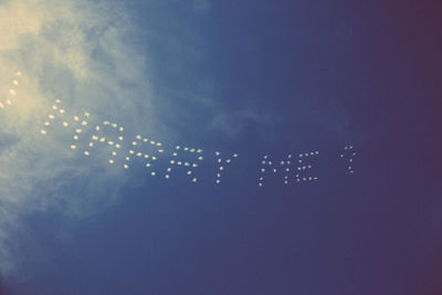 Low angle view of illuminated lighting equipment against blue sky