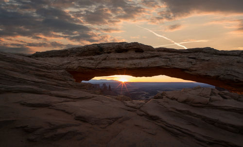 Rock formation against cloudy sky during sunset