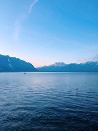 Scenic view of sea and mountains against blue sky