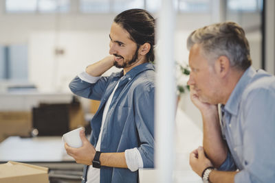 Smiling young businessman holding coffee cup in new office