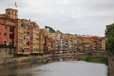 Buildings by river in town against sky