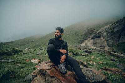 Young man standing on mountain against sky