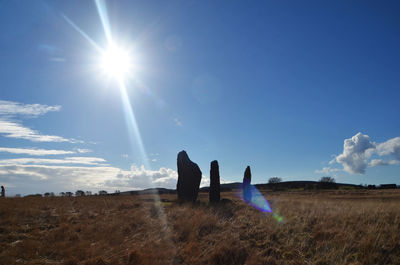 Silhouette people on field against blue sky