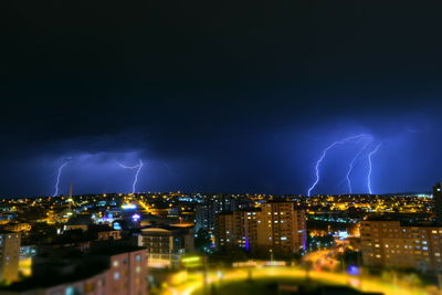 Lightning over illuminated cityscape at night