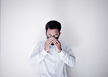 Portrait of young man standing against white background