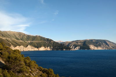 Scenic view of sea and mountains against blue sky