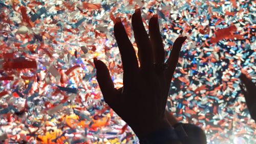 Cropped hand of woman against confetti at music concert