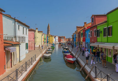 Boats moored in canal amidst buildings against sky