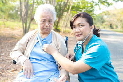 Smiling doctor examining senior woman at park