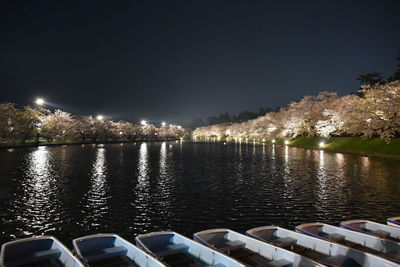 River by illuminated city against sky at night