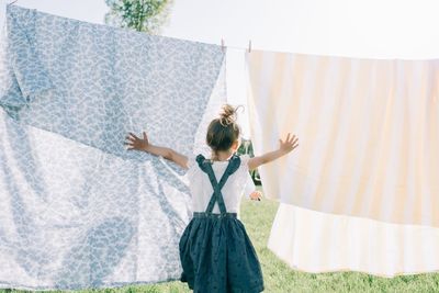 Young girl running through the washing on the line in the sun