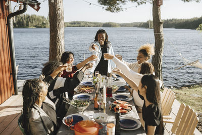 Smiling female friends celebratory toasting wine during party