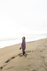 Woman standing on sand at beach against clear sky