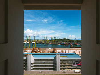 View of city by sea against sky seen through window