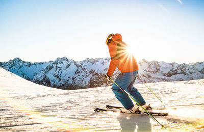 Full length of man standing on snowcapped mountain against sky