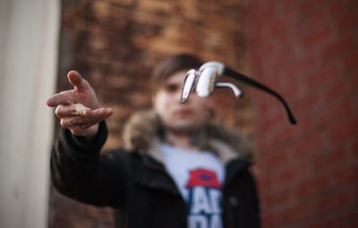 Man throwing eyeglasses against building