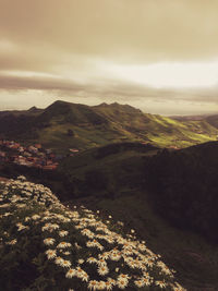 Scenic view of landscape against cloudy sky during sunset