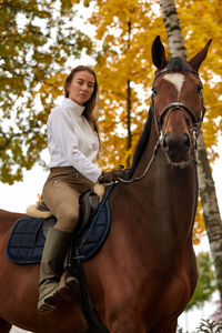 Young woman riding horse on field