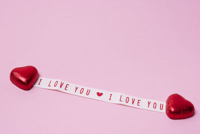 Heart-shaped candies and love message on pink background