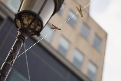 Low angle view of electric lamp hanging on building