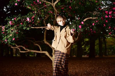 Portrait of woman standing by flowering tree