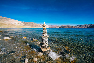 Scenic view of sea and rocks against blue sky