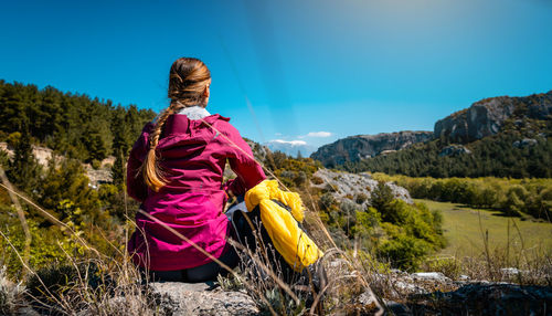 Rear view of woman standing on mountain against sky