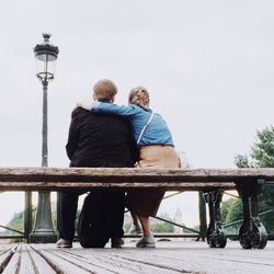 Rear view of couple sitting against sky