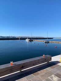Sailboats in sea against clear blue sky