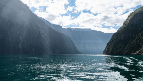 Scenic view of sea by mountains against sky