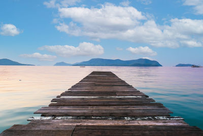 Pier on sea against cloudy sky