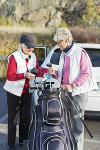 Happy senior women selecting golf clubs from bag