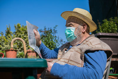 Side view of man sitting on chair wearing face mask