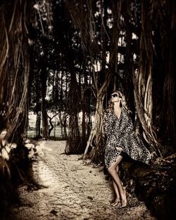 Full length of seductive woman standing amidst trees in forest