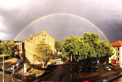 Rainbow over buildings in city during rainy season