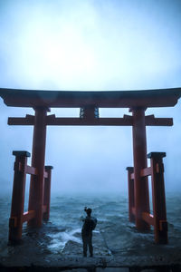 Rear view of man standing on cross against sky