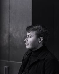 Portrait of young man looking away against wall