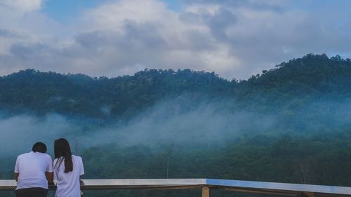 Rear view of couple on mountain against sky