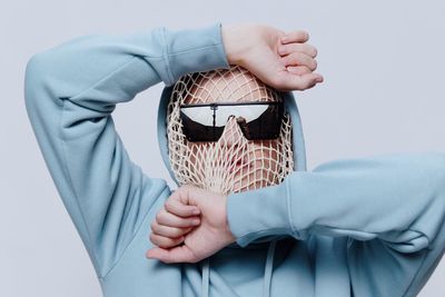 Man wearing mesh bag against gray background