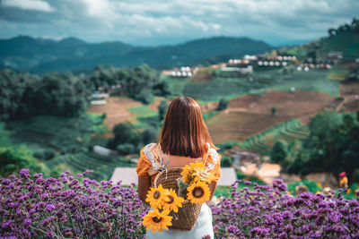 Rear view of woman looking at view of flowering plants