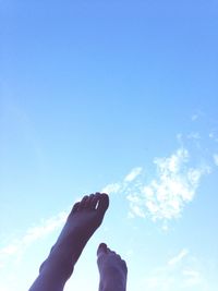 Low angle view of person hand against blue sky