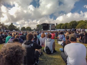 Rear view of people enjoying music concert against sky