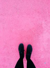 Low section of people standing against pink wall