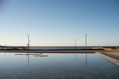 View of pool and sea against clear blue sky
