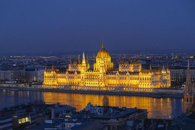 Illuminated city against clear sky at dusk