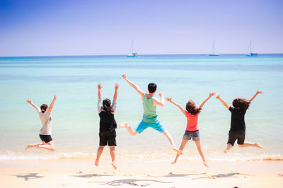 Friends at beach against clear sky