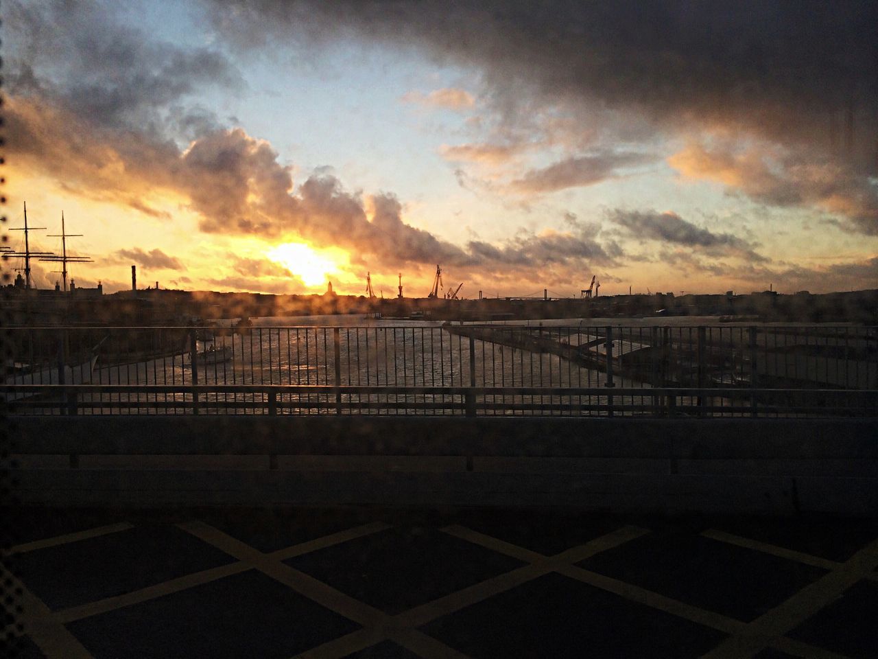 sunset, orange color, sky, sun, cloud - sky, silhouette, railing, water, fence, scenics, built structure, beauty in nature, connection, nature, tranquility, architecture, tranquil scene, sunlight, idyllic, cloud