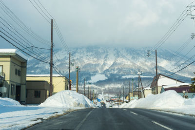 Road by snow covered mountains against sky